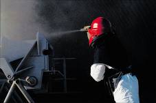 worker blasting and coating metal